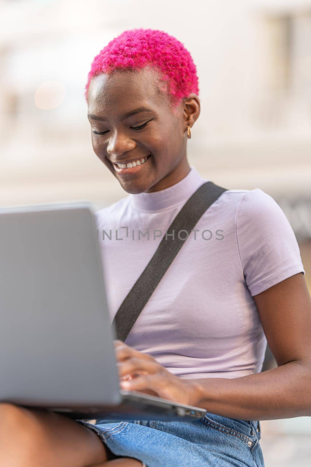 Vertical portrait of smiling young afro woman using a laptop by ivanmoreno