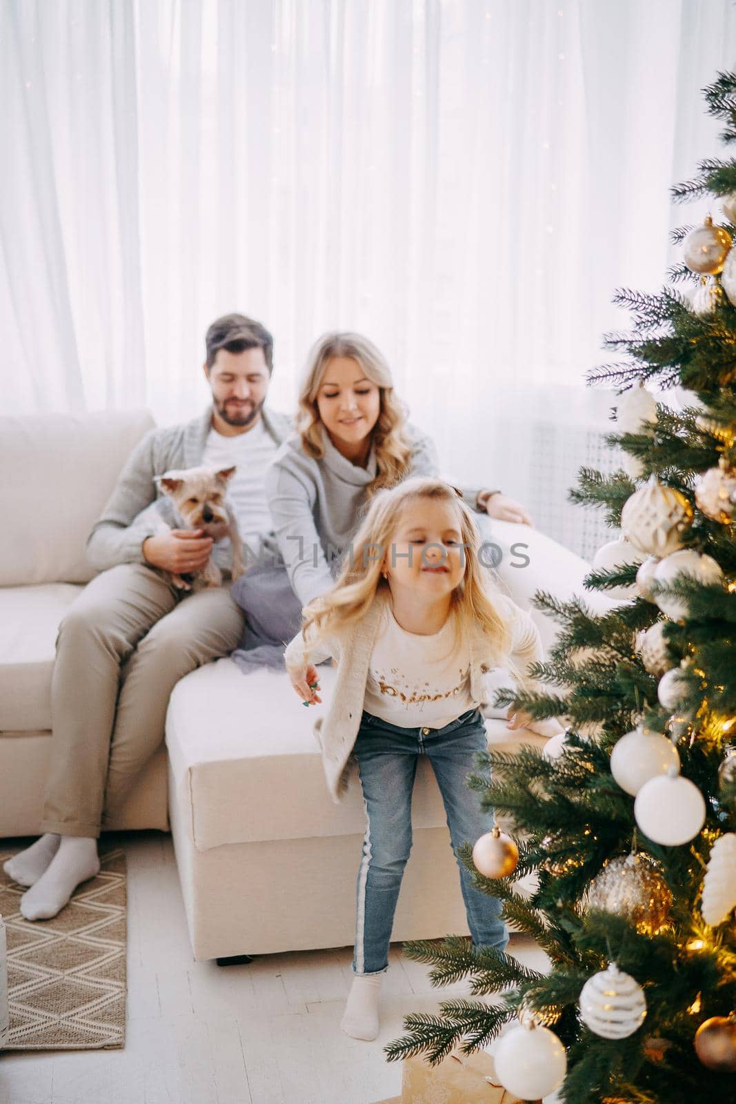 Happy family: mom, dad and pet. Family in a bright New Year's interior with a Christmas tree. by Annu1tochka