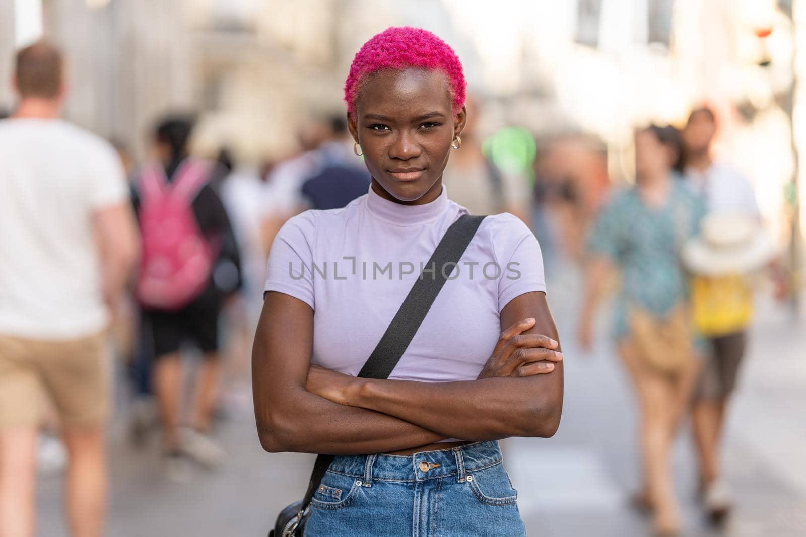 Portrait of a serious african woman looking at camera with the arms crossed in the city street