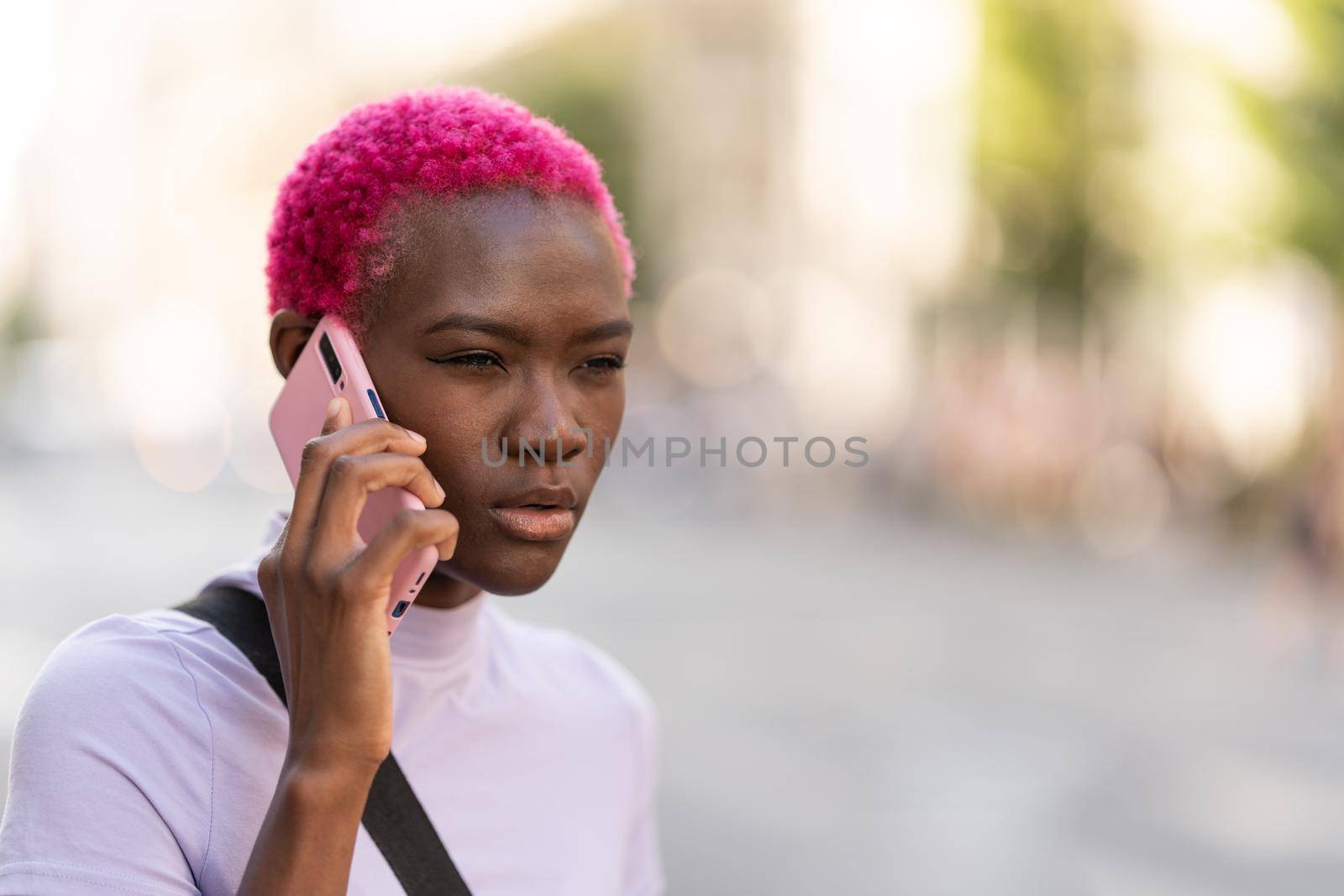 Afro woman with a distrustful expression talking on a mobile by ivanmoreno