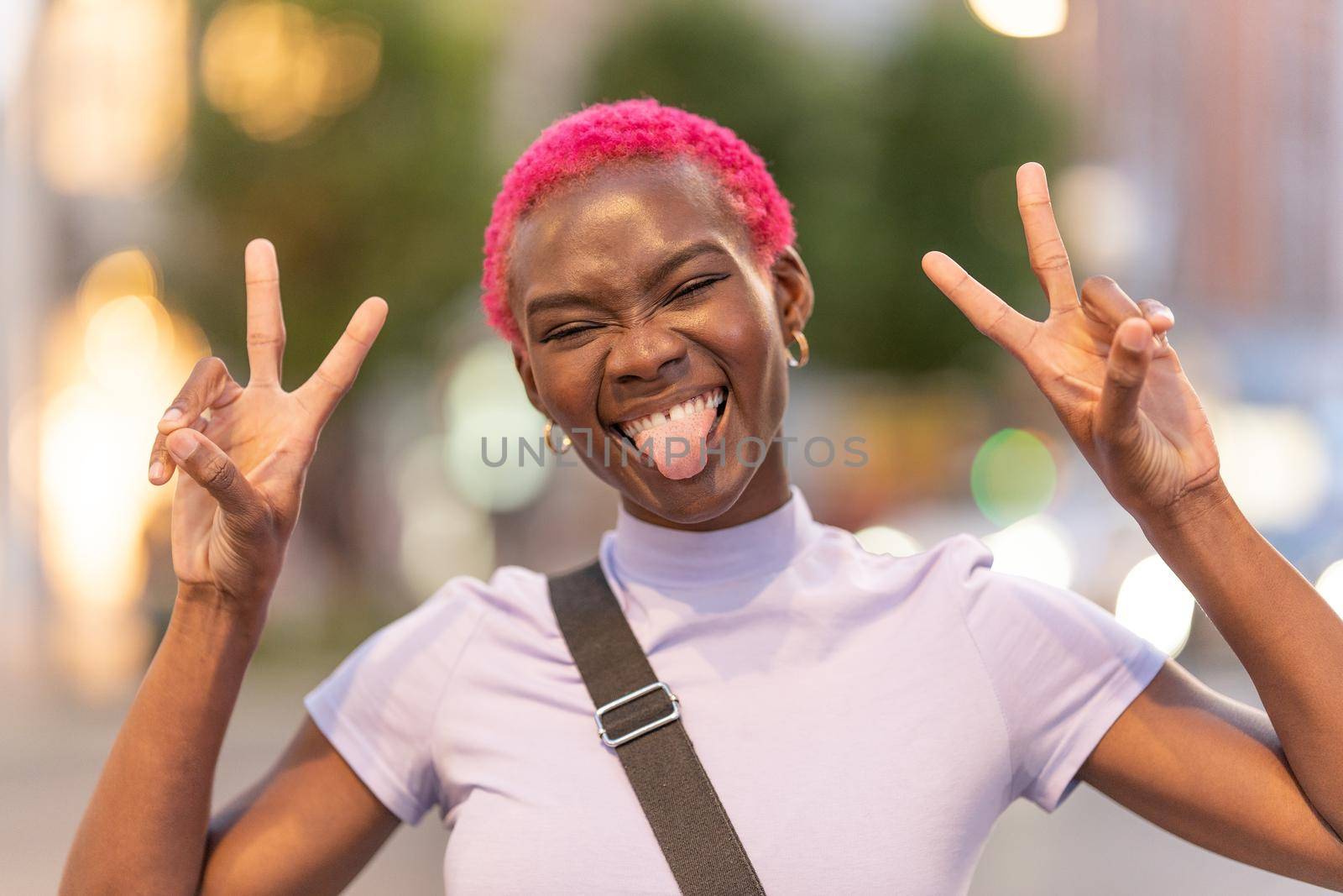 Stylish african woman raising the fingers gesturing victory while grimacing to the camera
