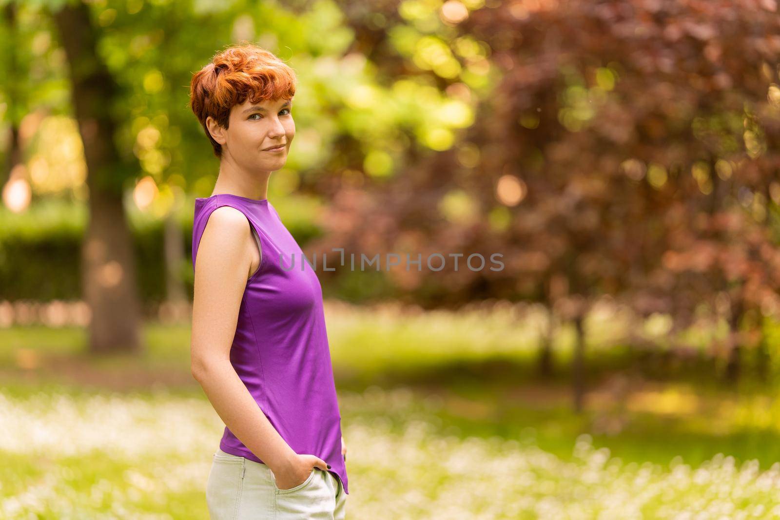 Portrait with copy space of a non-binary person turning to smile to the camera in a park in summer