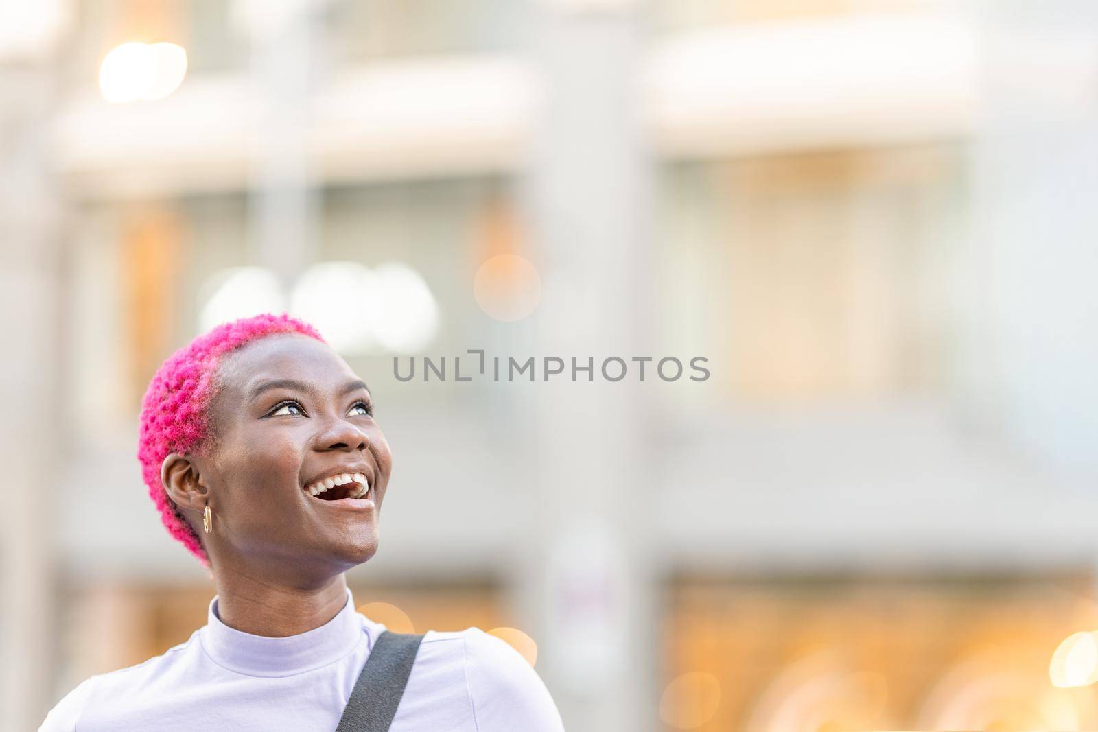 Portrait with copy space of a beauty smiling young african woman looking up to the sky outdoors