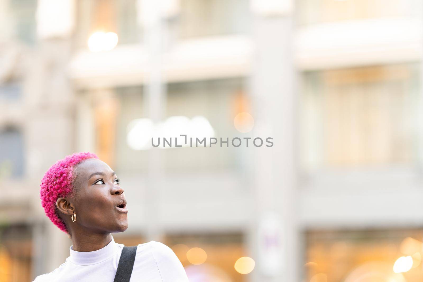 Young african woman looking up with surprised expression outdoors