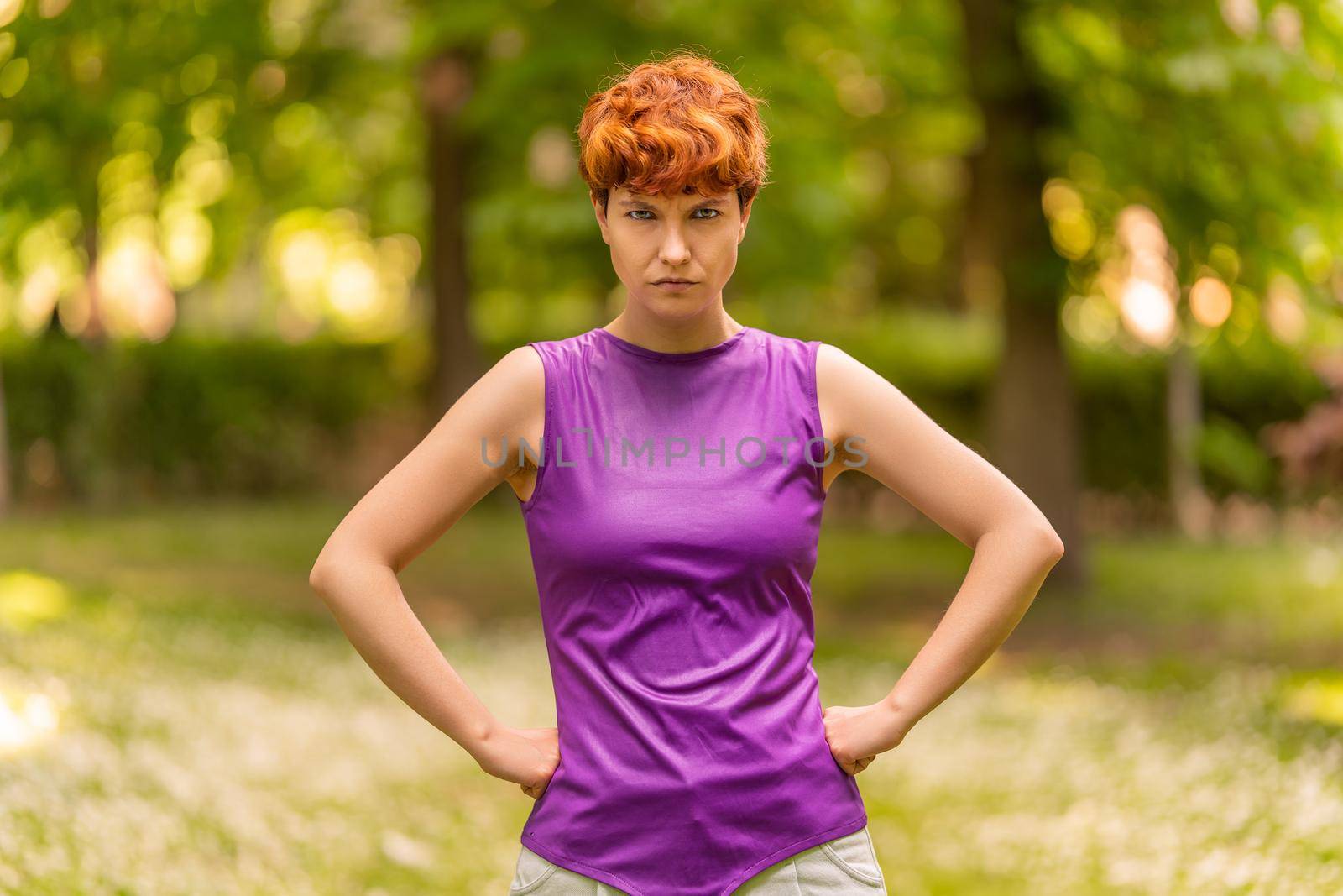 Non-binary gender person with angry expression in a park by ivanmoreno