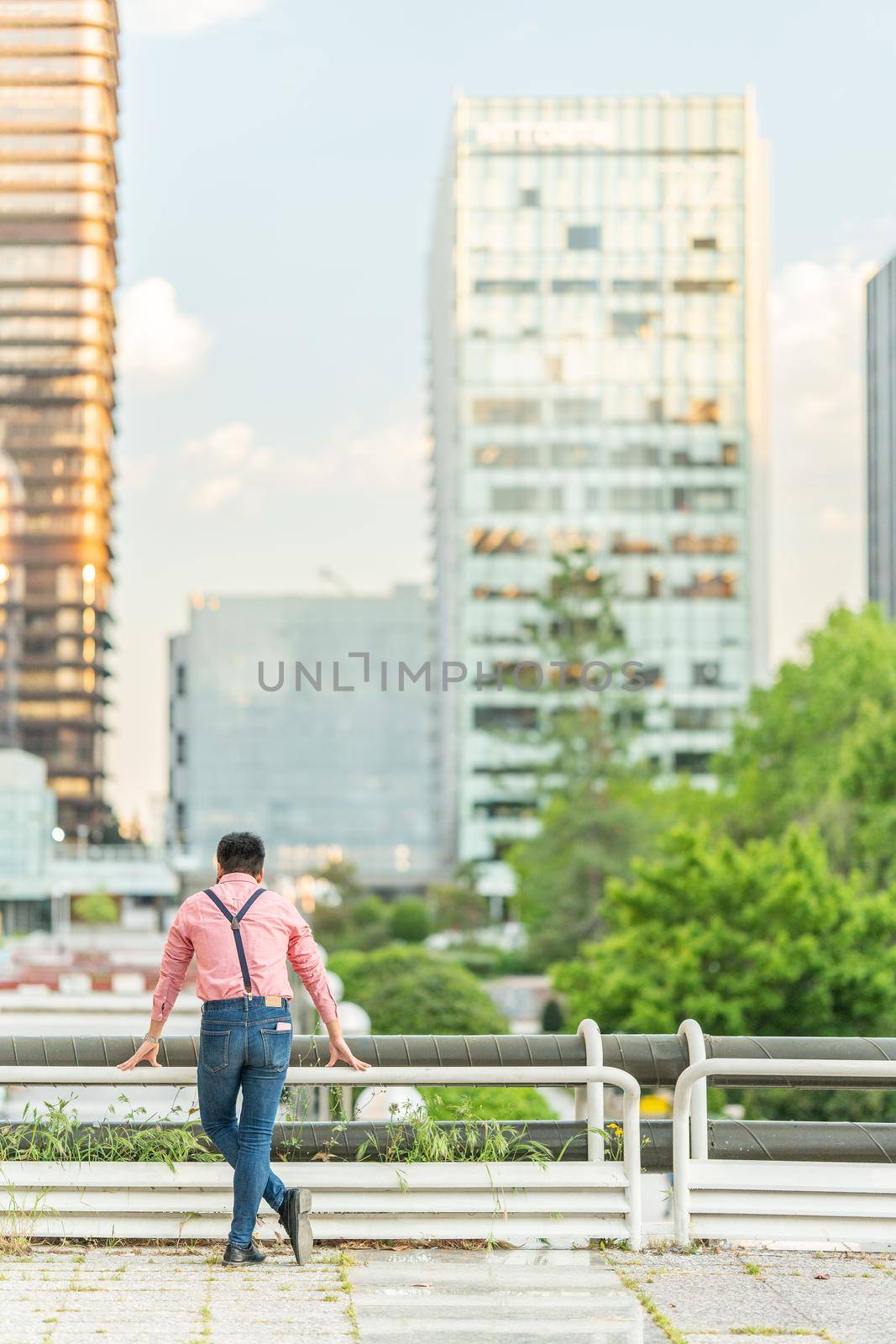 Vertical photo of the back of an asian man looking the city landscape form a viewpoint