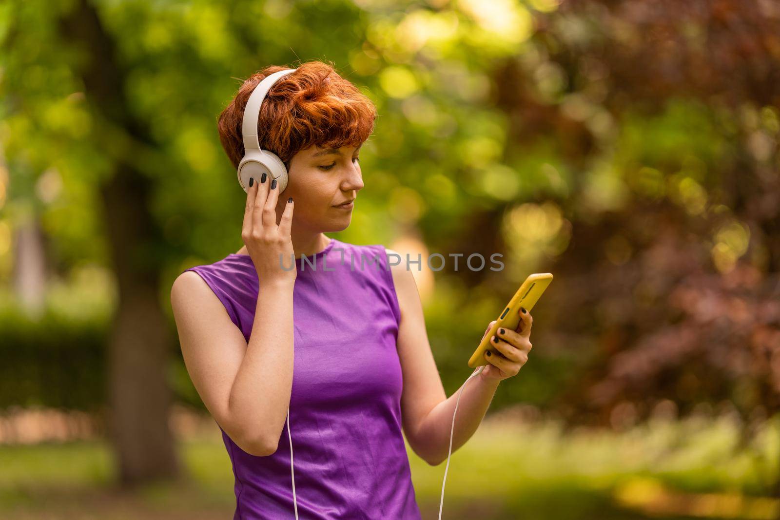 Androgynous woman using smartphone and listening to music by ivanmoreno