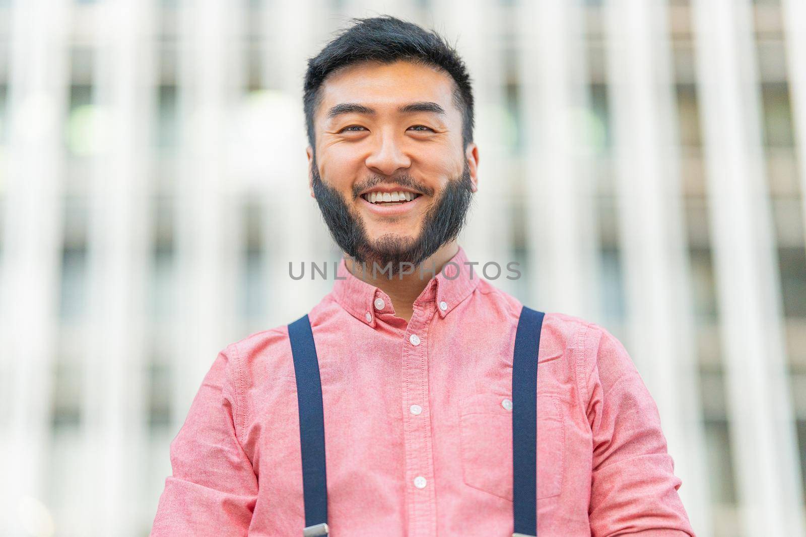 Low angle view portrait of a asian man in casual clothes smiling to the camera outside a city