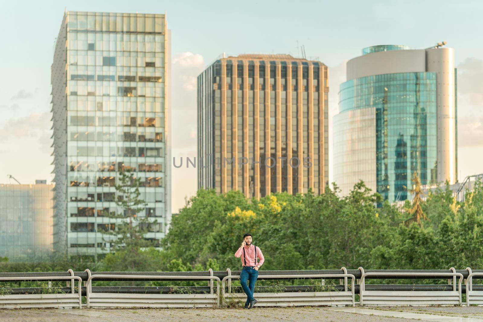 Asian man talking to his mobile phone from a viewpoint overlooking an urban landscape