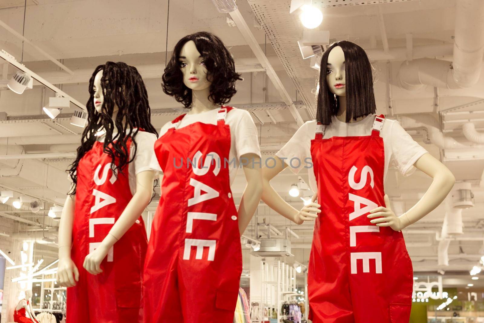 Female mannequins in woman red dungarees in fashion clothing store, black friday sale shopping concept, seasonal offer promo