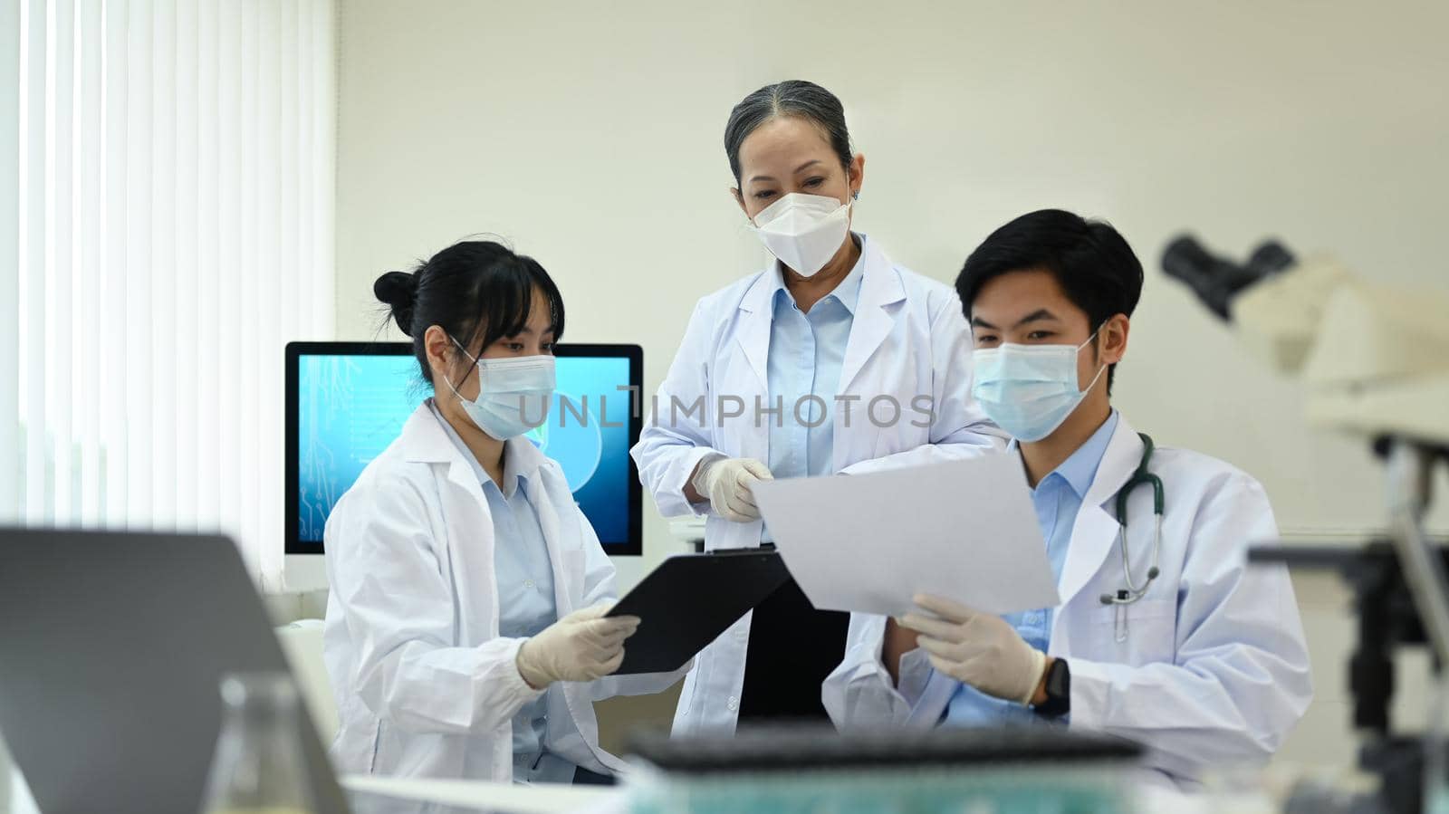 Team of young research scientists and senior supervisor discussing about new test results, working together in laboratory.