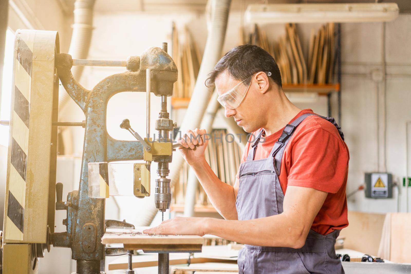 Focused carpenter drilling steel in professional workshop by ivanmoreno