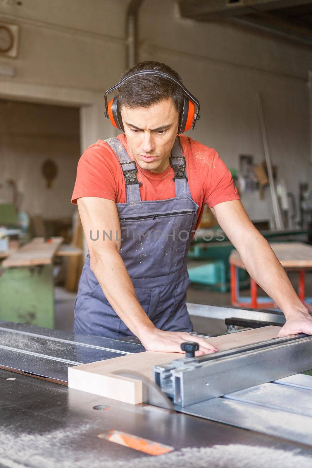 Woodworker cutting plank with table saw in workshop by ivanmoreno