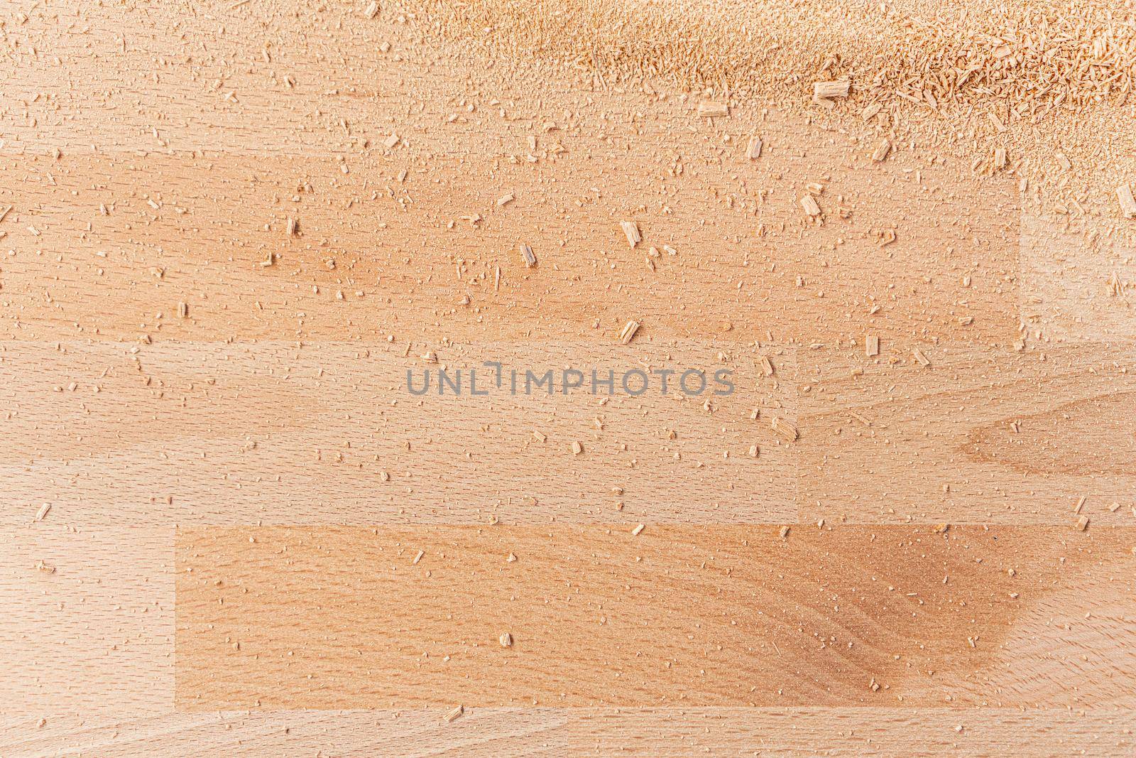 Textured full frame backdrop of wooden desk with natural pattern and sawdust spread on surface