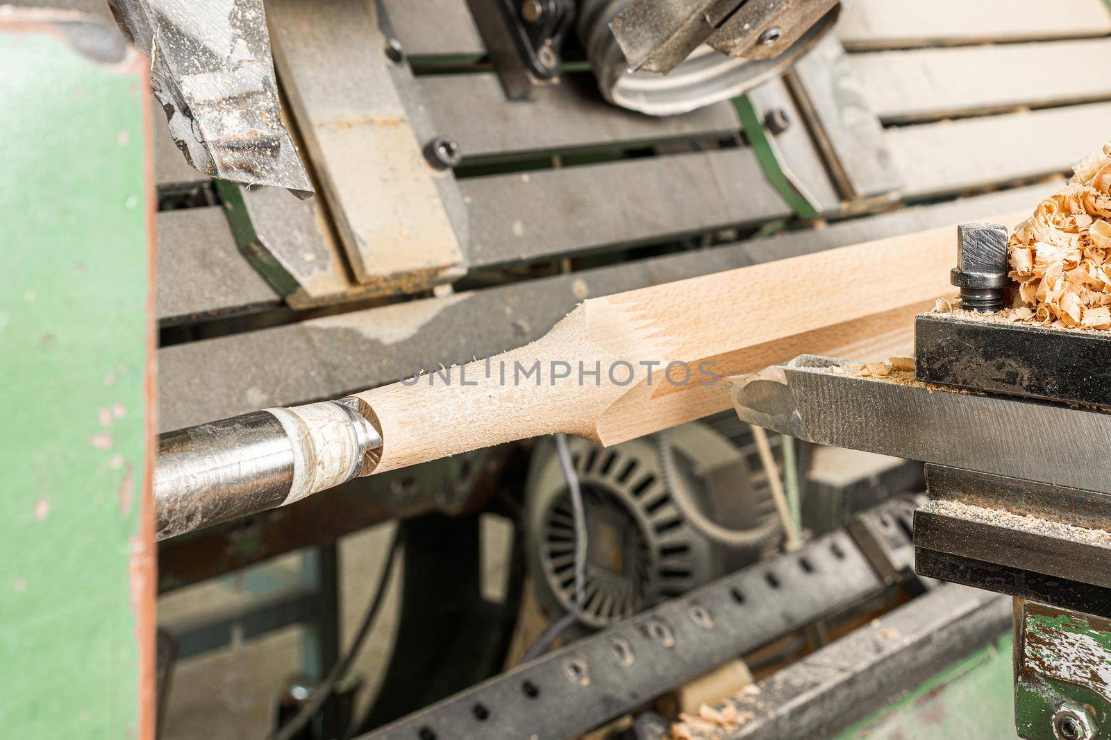 Lathe with tools processing wooden piece while cutting shape symmetrical around axis in joinery