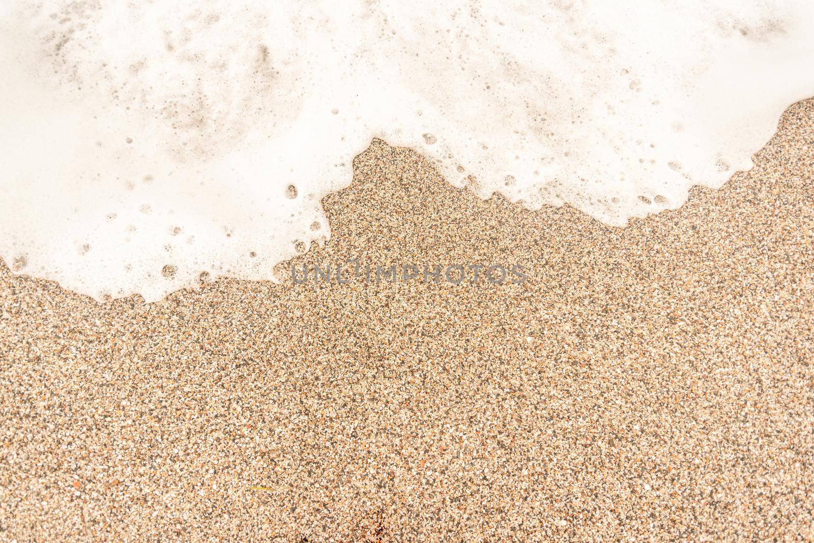 Top view full frame of textured background of brown sand with sea foam on beach