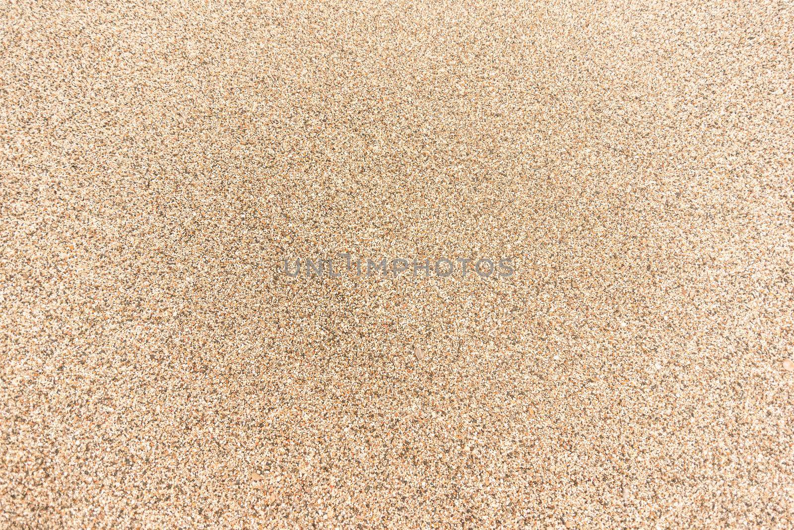 Full frame background of textured surface of sand with coarse grains of yellow color