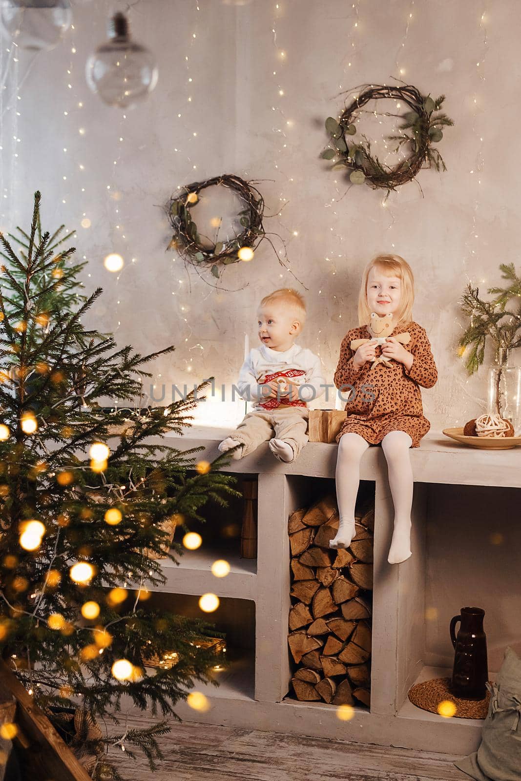 Little brother and sister play on Christmas eve in a beautiful house decorated for the New Year holidays. Children are playing with a Christmas gift. by Annu1tochka