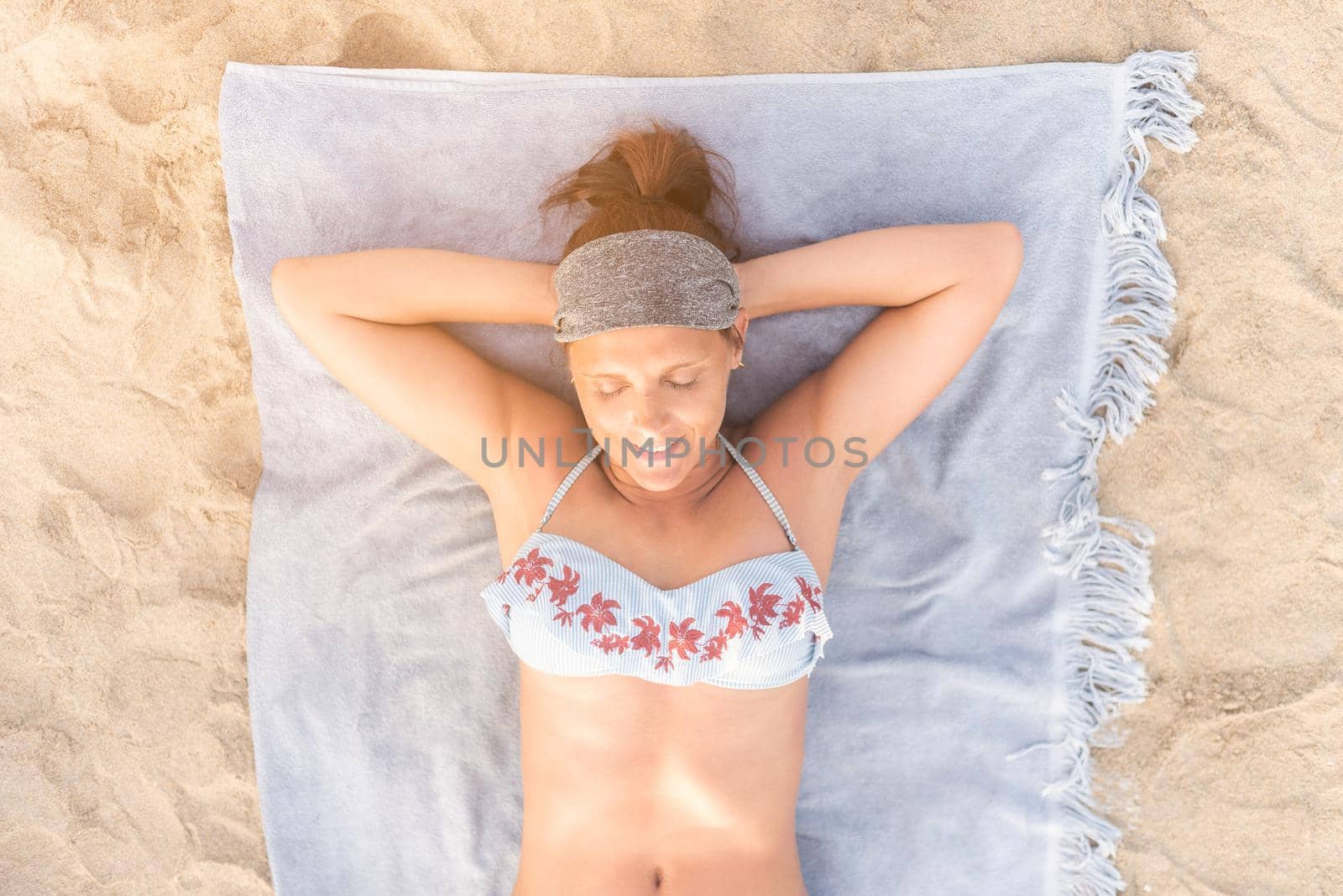 Smiling woman in swimwear sunbathing on beach by ivanmoreno