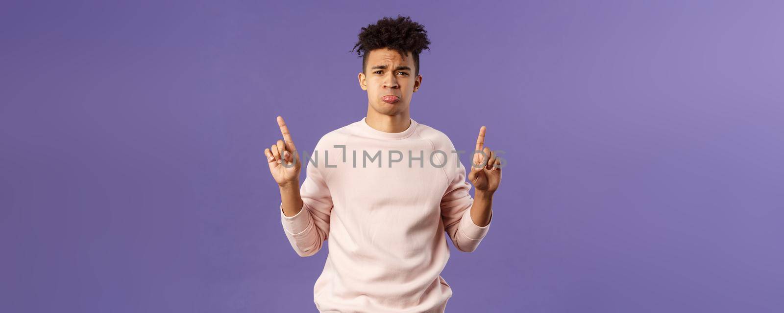 Portrait of gloomy, pouting frowning hipster guy dont have something he wants, pointing fingers up at super cool expensive thing, asking for it, trying receive compassion, purple background by Benzoix