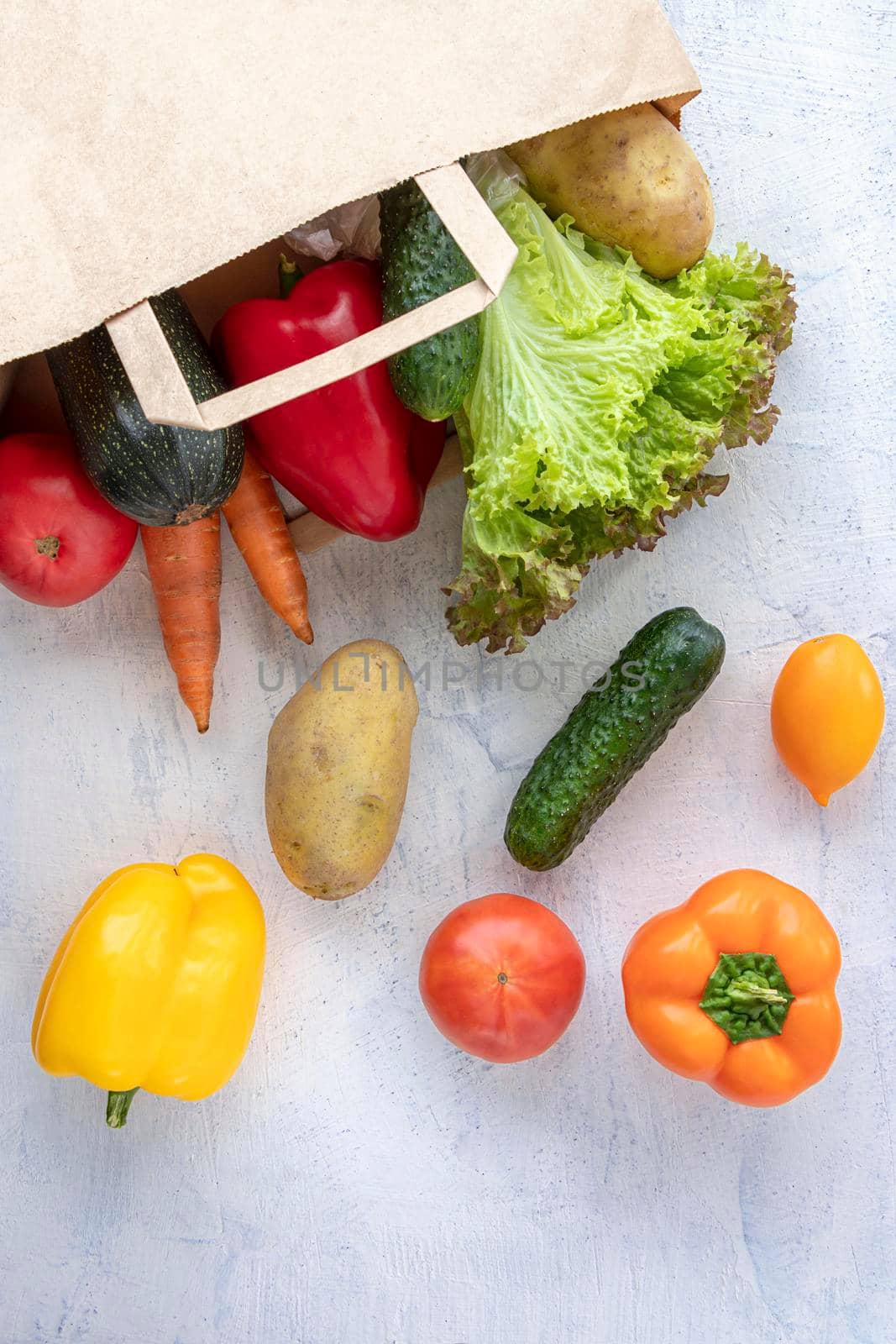 vertical photo with paper bag and vegetables. lettuce, cucumber, potato, tomato, bell pepper and eco bag on the table. by Leoschka