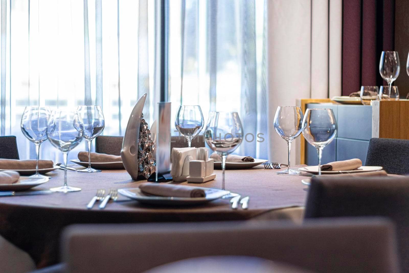 an empty table with dishes in a cafe or restaurant against the backdrop of a large window. by Leoschka