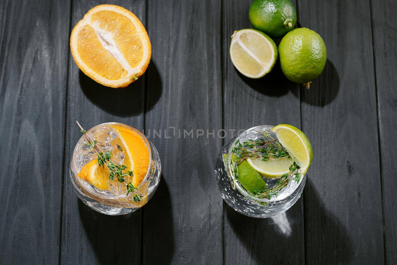 two glasses with an alcoholic cocktail on a wooden dark background. hard seltzer is a low-alcoholic drink. Strong seltzer cocktails with lime. Alcoholic cocktail tonic clear. hard seltzer is a low-alcohol drink consisting of alcohol, carbonated water and fruit, berry and herbal flavorings. Top view