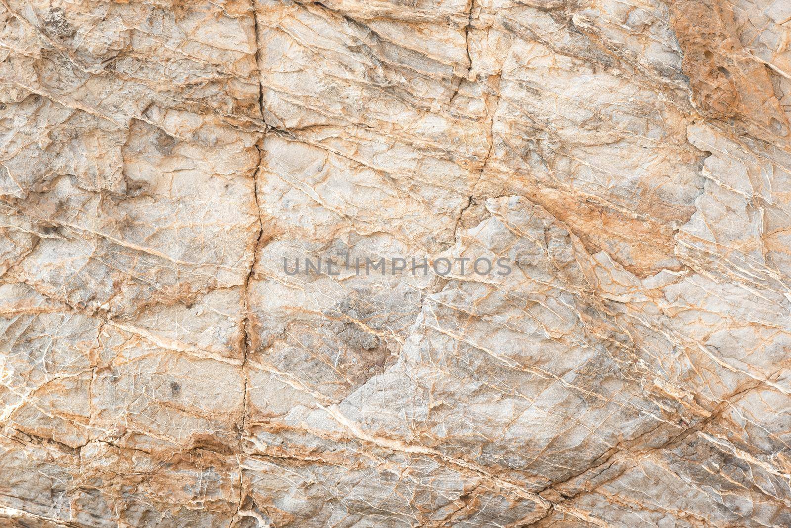 Textured backdrop of rough rocky gray uneven surface with cracks and scratches in daylight