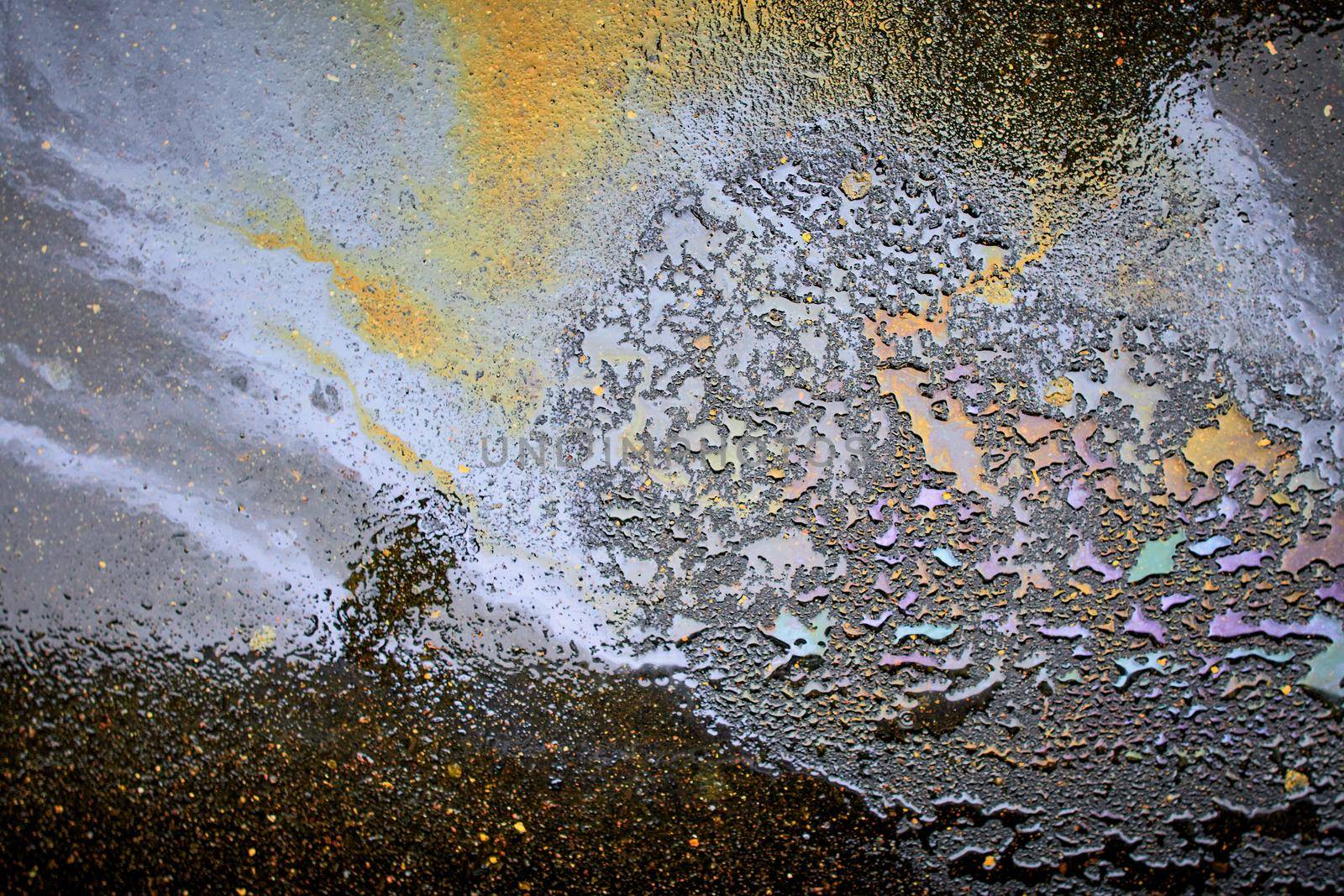 Oil stain on the asphalt, rainbow-shaped colored gasoline stains on an asphalt road as a texture or background
