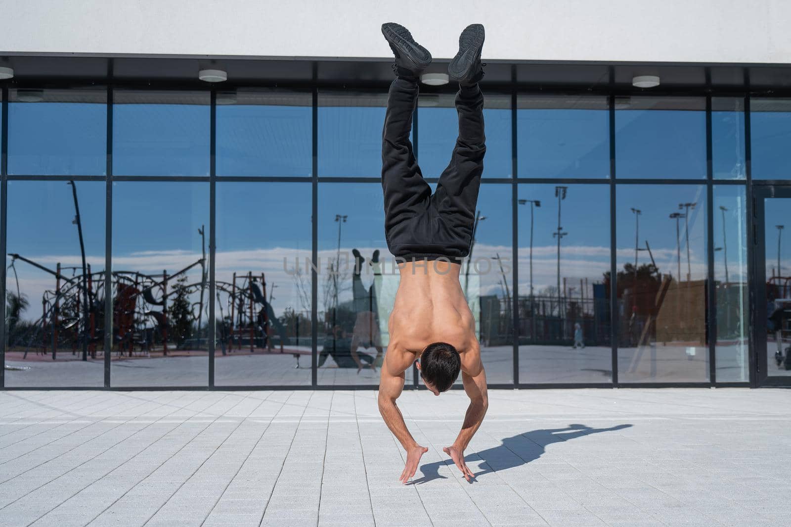 A man doing a handstand outdoors against of panoramic windows