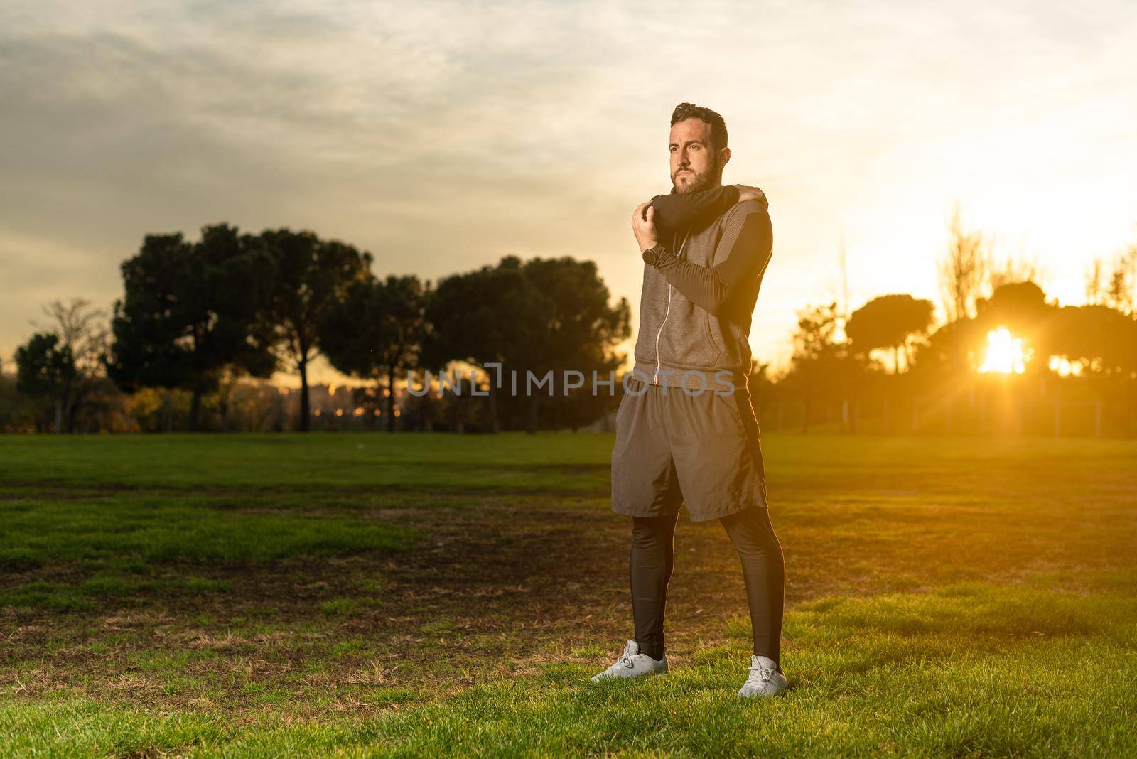 Serious male athlete warming up before training in park by ivanmoreno