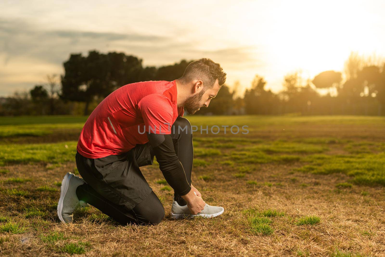 Sportsman tying shoelaces before running training on lawn by ivanmoreno