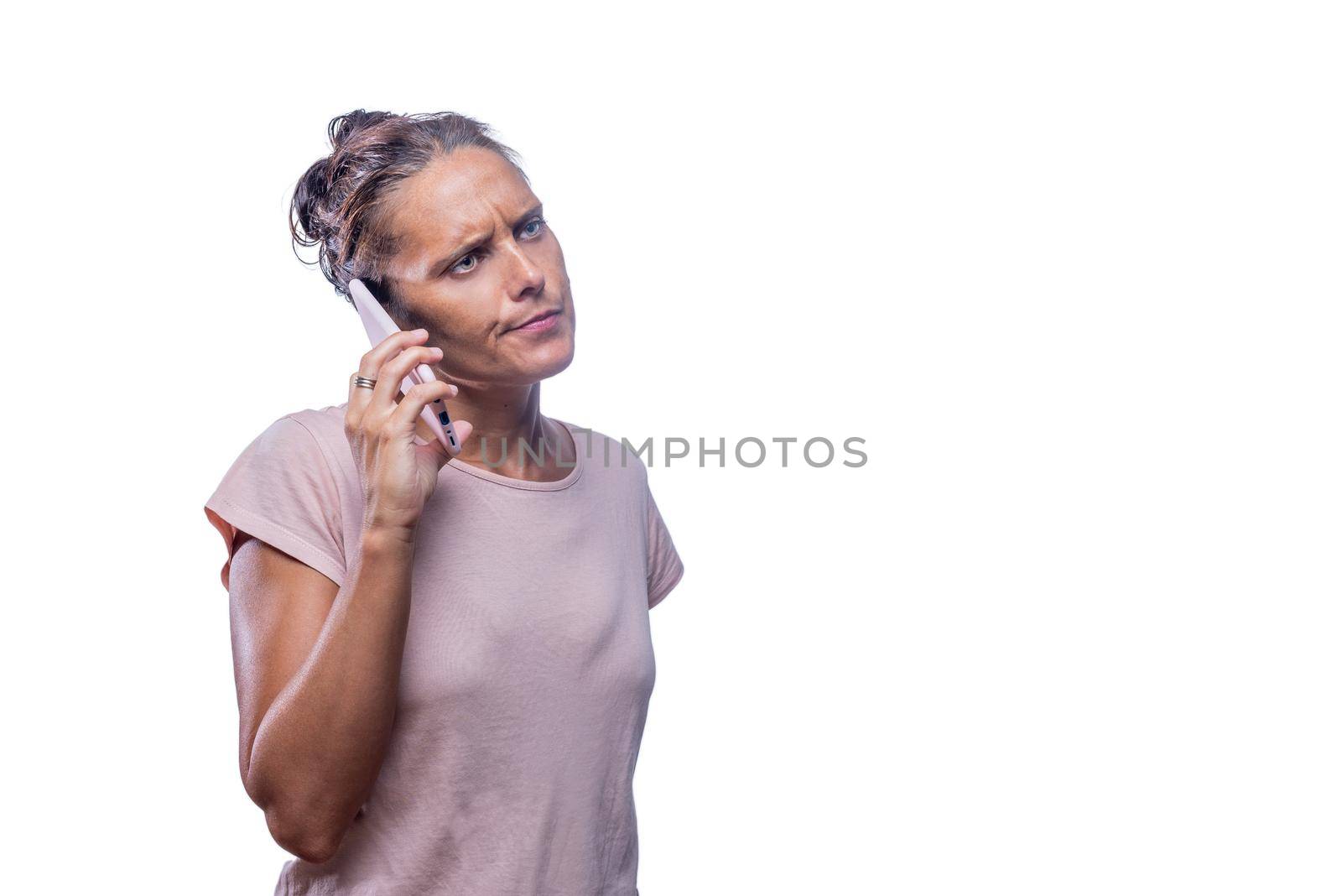 Front view of an annoying green-eyed woman talking with her phone while looking away on a white background with copy space.