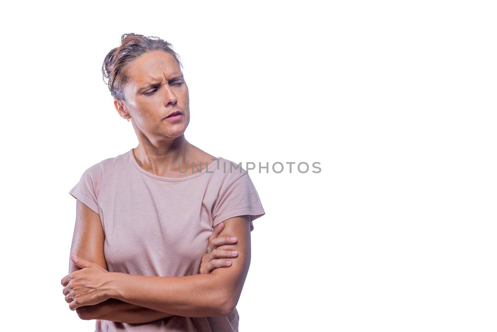Front view of a distrustful woman with crossed arms on a white background looking to a side with copy space.
