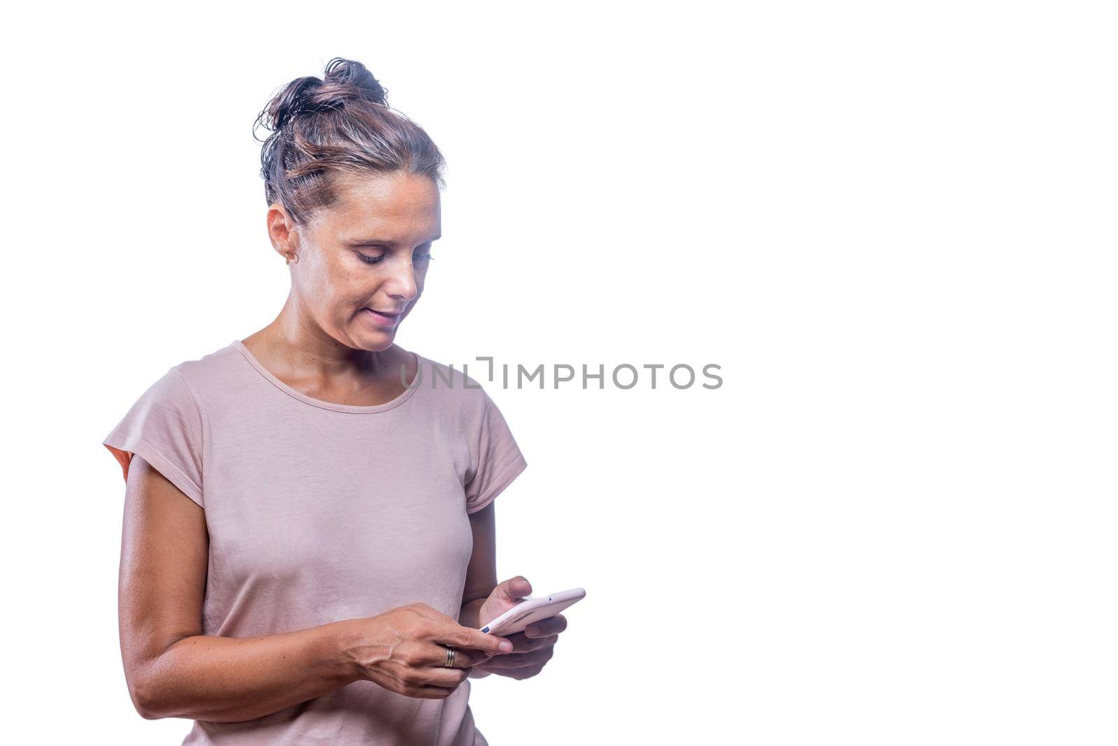 Front view of a green-eyed woman using her mobile phone looking it on a white background with copy space.