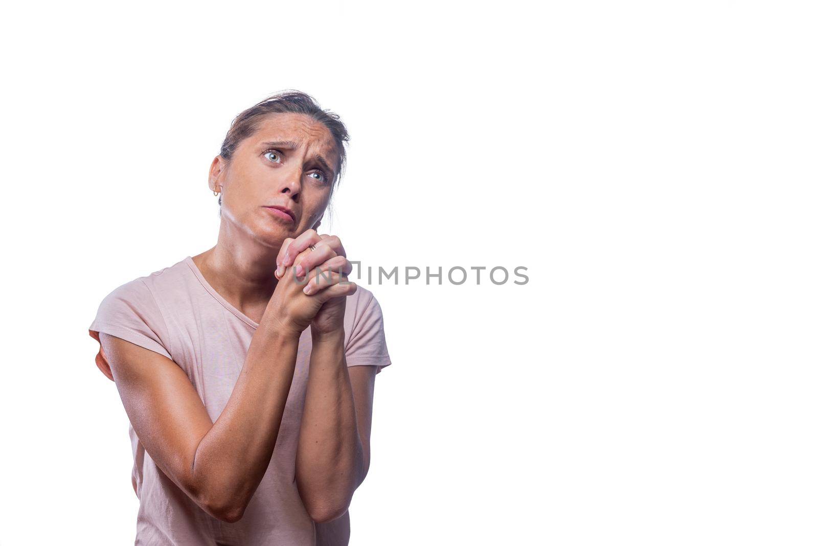 Front view of a green-eyed woman begging and praying with hands together with hope expression on face on a white background with copy space.