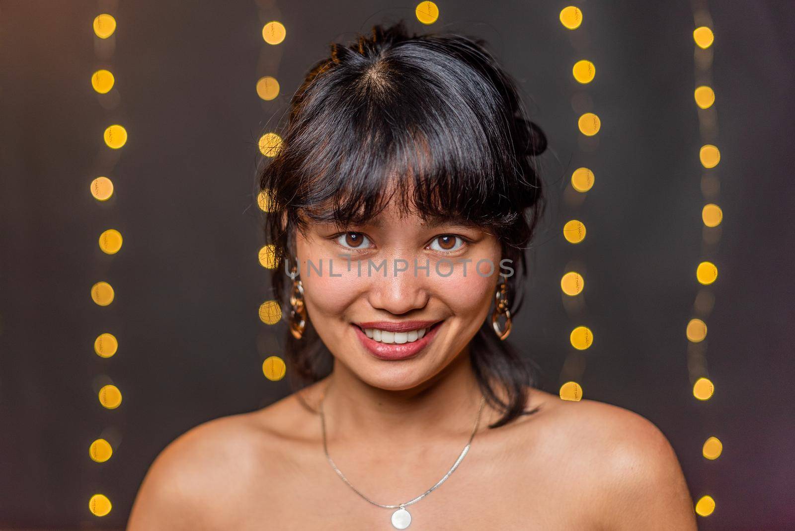 An asian woman smiling looking at camera with blurred background by ivanmoreno