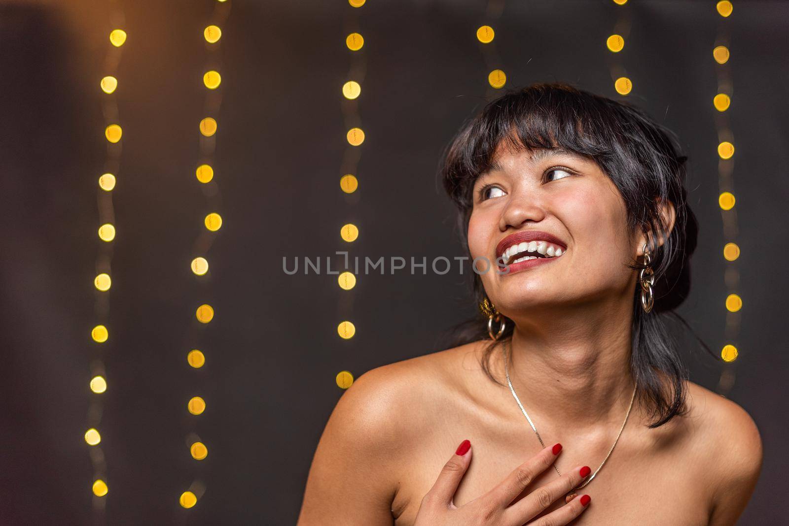 An asian woman smiling looking away with a blurred background by ivanmoreno