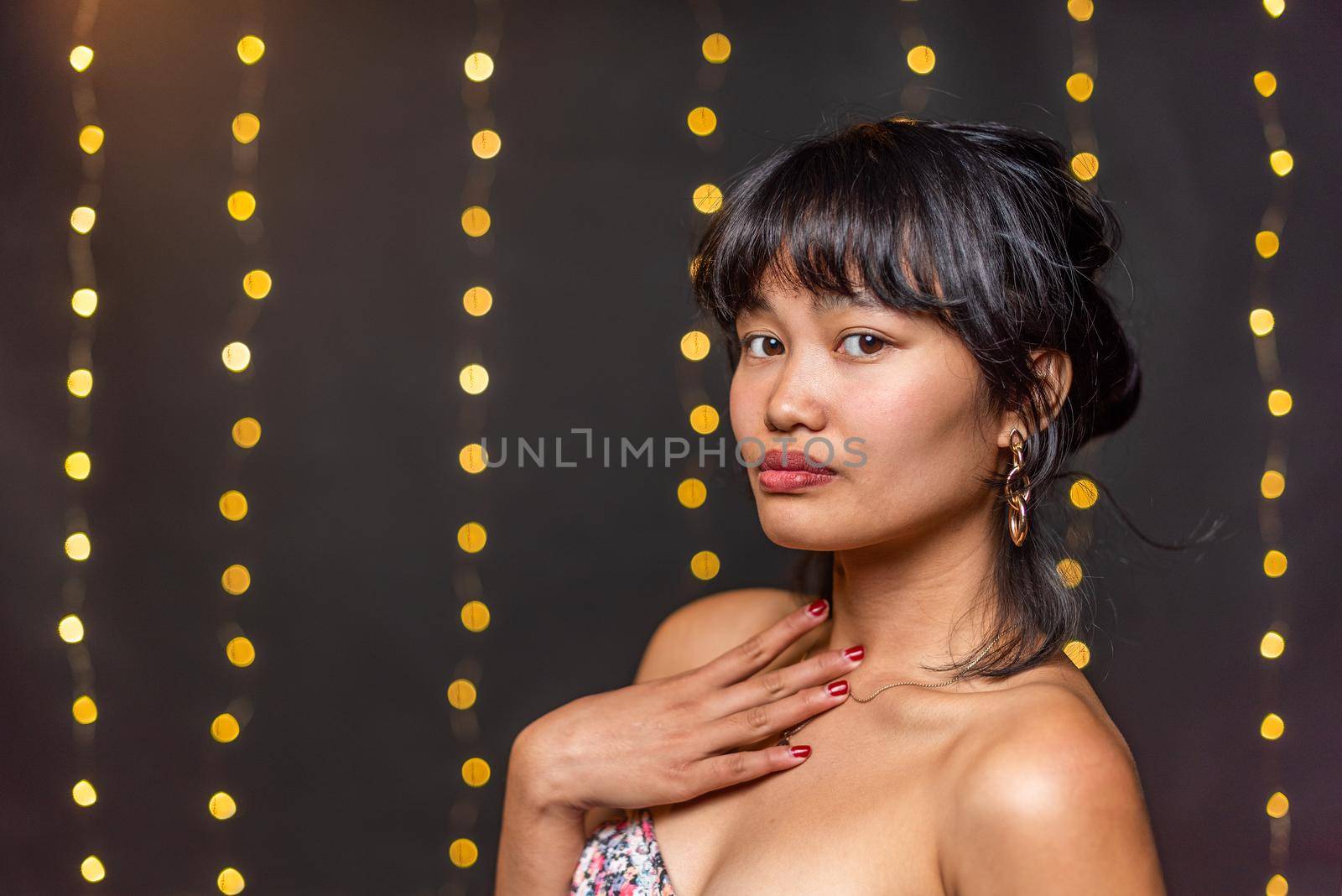 Portrait of an asian young woman posing and looking at camera with a blurred light background with copy space