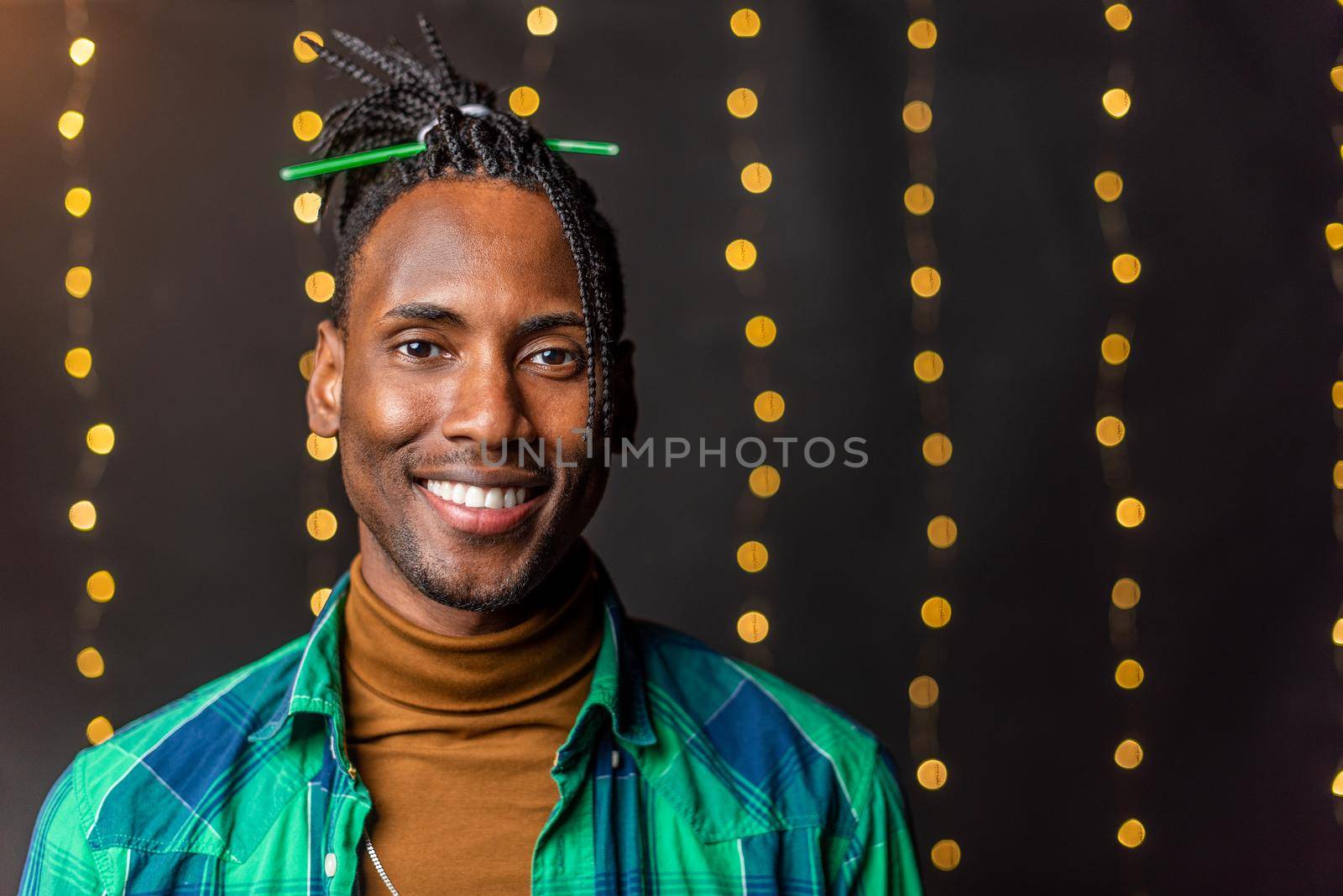 Portrait of a happy young African American with braids looking at the camera with a blurred light background.
