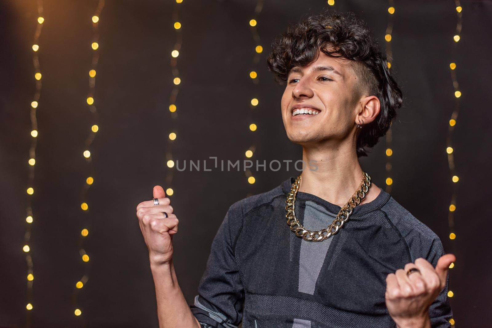 A happy caucasian young man dancing with clenched fists against a background of blurred lights.