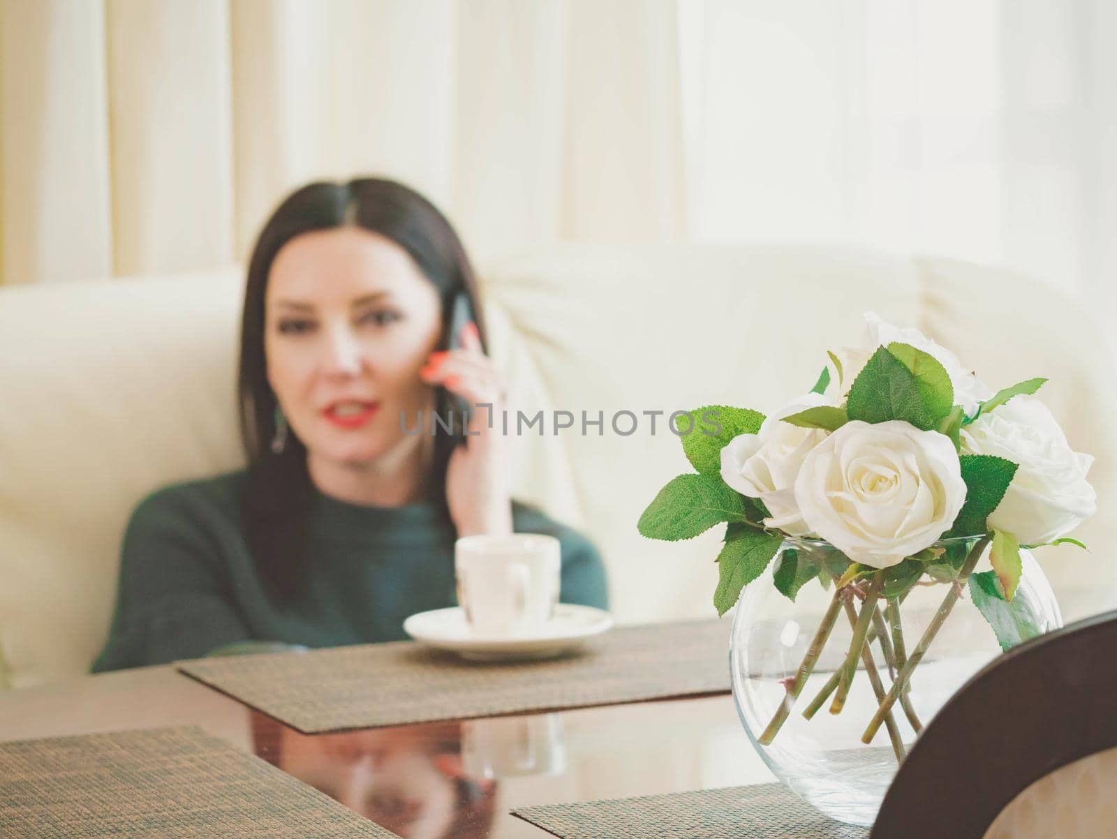 Woman talking on phone in the kitchen. Beautiful mature young female professional having casual conversation on smartphone. Caucasian model.