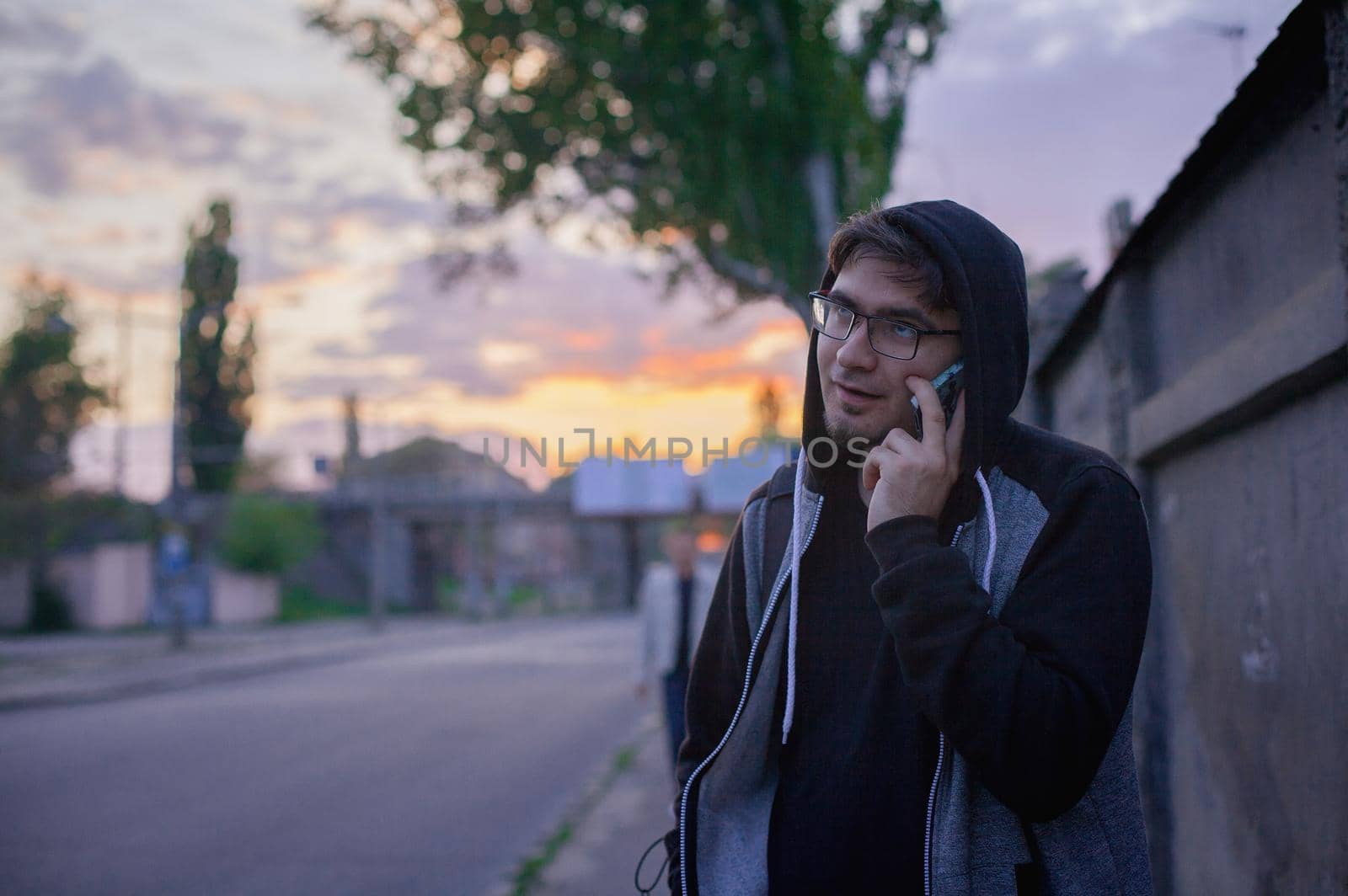 Portrait of tired young man making a boring conversation on cellphone on the street