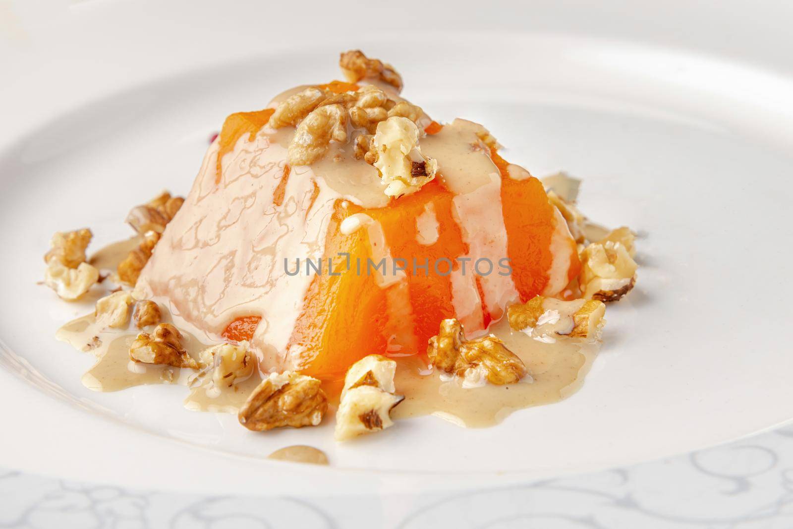 Traditional pumpkin dessert with tahini and walnuts on a white porcelain plate by Sonat