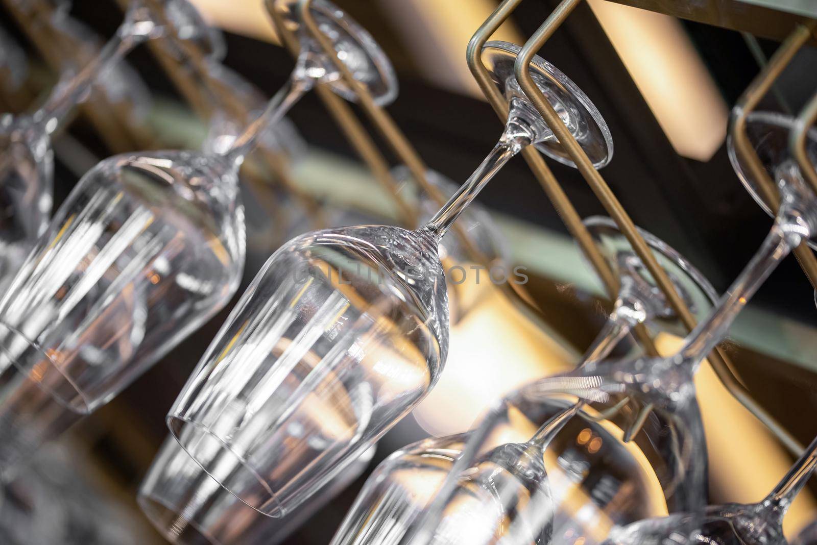 Cocktail Glasses hanging above the bar in the restaurant. Empty glasses for wine. Wine glasses in shelf above a bar rack in restaurant.