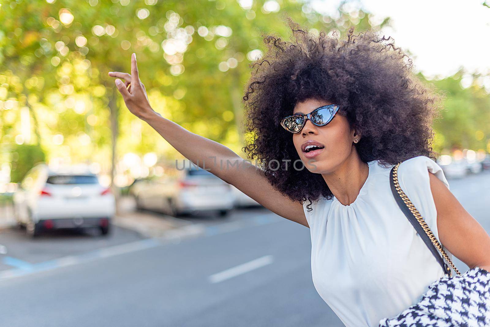 businesswoman leaning out of the road to hail a taxi by ivanmoreno