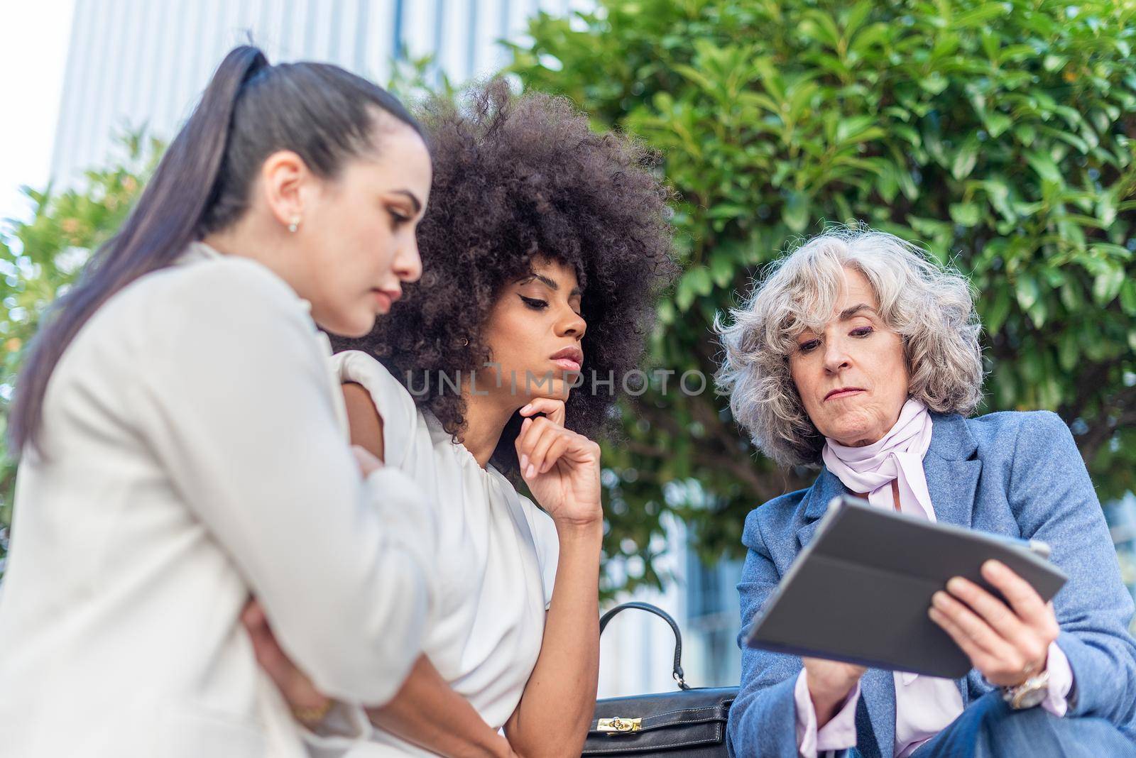 three female workers studying company information in the city by ivanmoreno