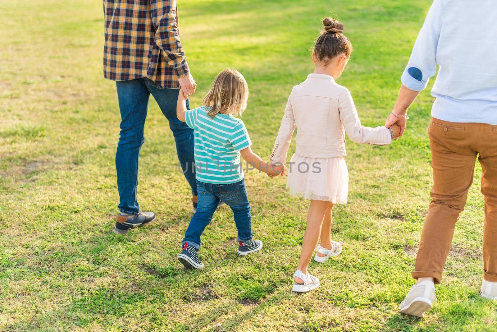 two children walking hand in hand with their dads by ivanmoreno