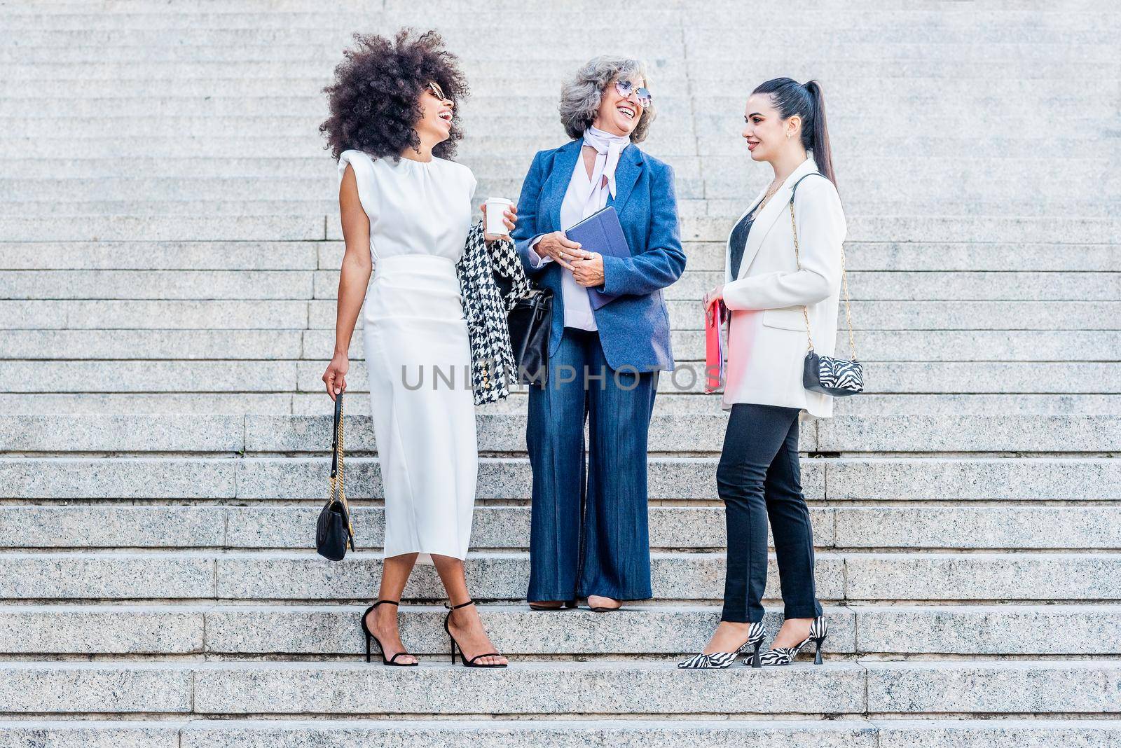 three businesswomen laughing while standing on the stairs, horizontal background