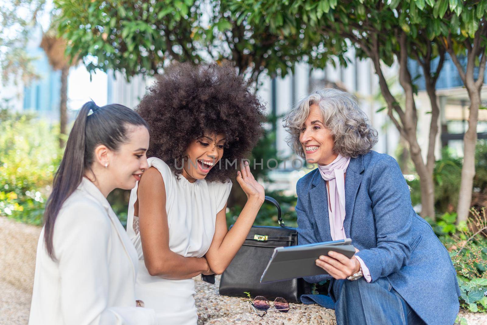 three female entrepreneurs having a good time watching something on the tablet, close up view